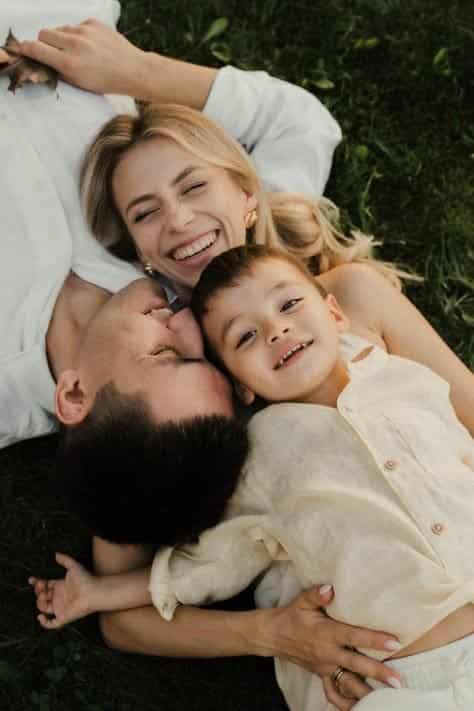 Visual Hook: A joyful, intimate overhead shot of a family lying closely together on gre...