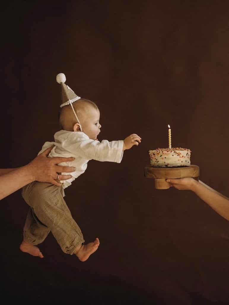Visual Hook: A whimsical, tender moment of a small child reaching for a birthday cake,...