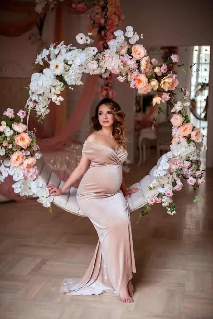 Visual Hook: A serene maternity portrait featuring a person seated on a floral-adorned...