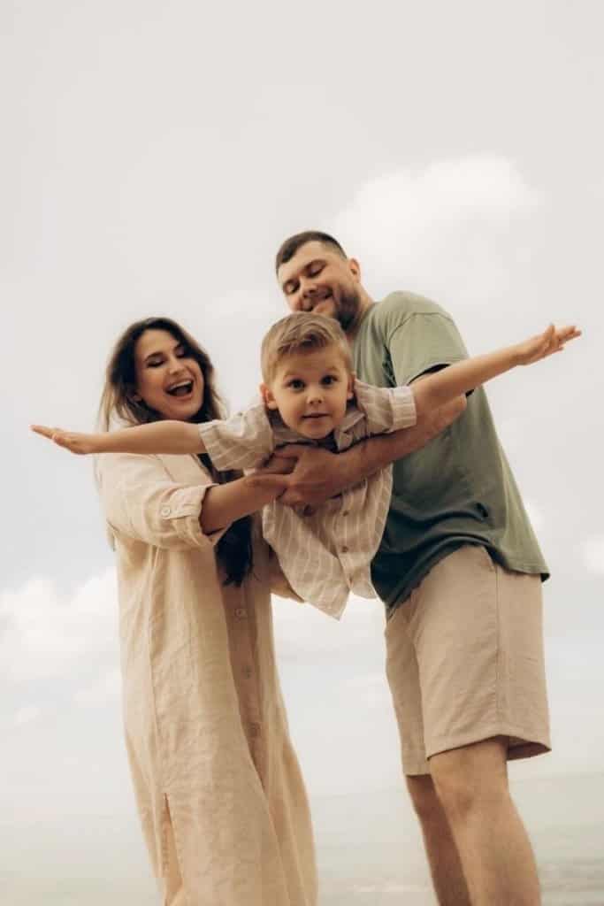 Visual Hook: A joyful family moment with a child "flying" between two adults against an...