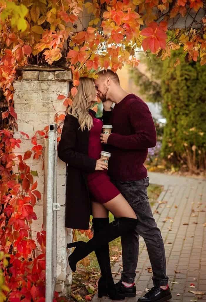 Visual Hook: A romantic embrace under a canopy of vibrant autumn leaves, highlighting t...